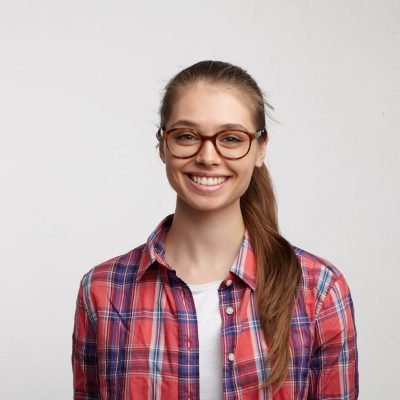 Headshot of attractive teenage girl with cute nice features and ponytail looking at camera and smiling cheerfully, enjoying good day and happy moments of her youth, dressed in stylish clothing